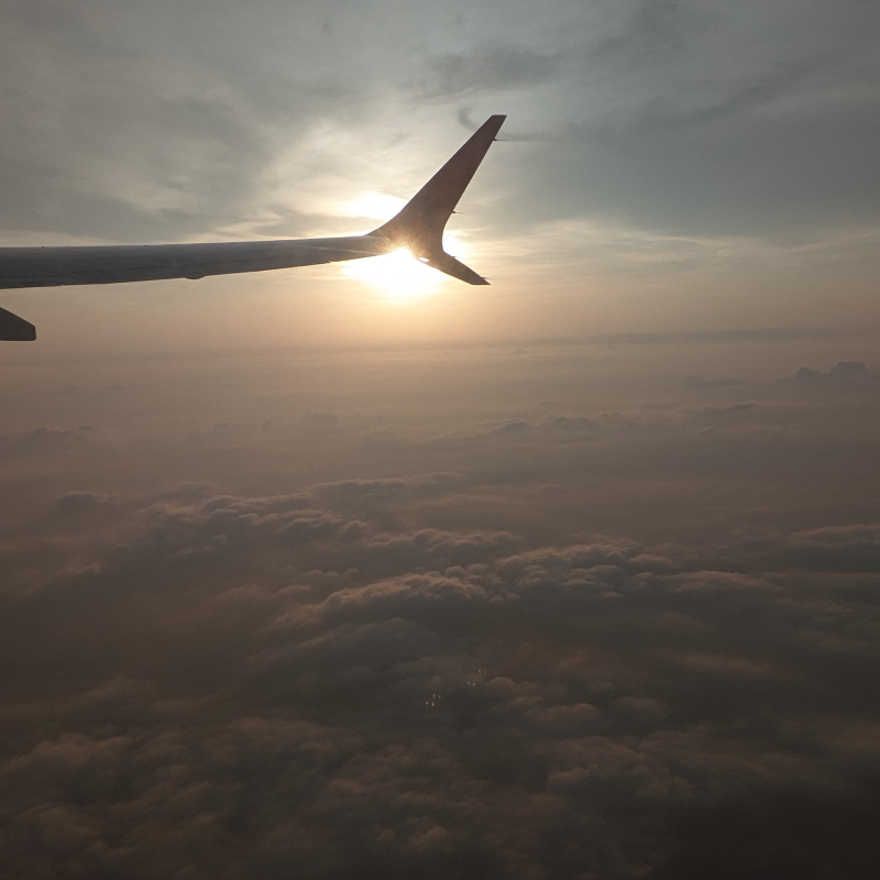 Plane wing above the clouds at sunset